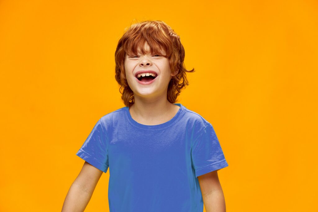 Criança sorrindo em frente a fundo laranja, simbolizando o crescimento do ensino bilíngue e o impacto positivo no desenvolvimento infantil.