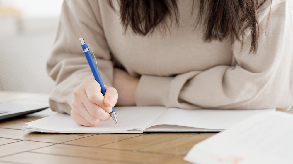 Pessoa escrevendo em caderno durante a preparação para o Cambridge Certificate Test.
