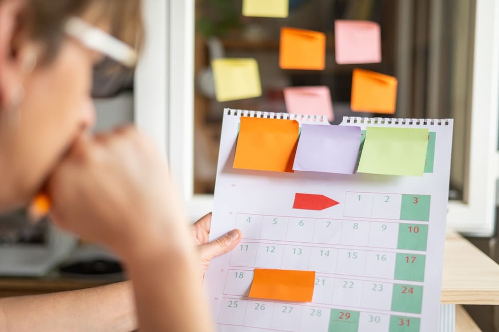 Calendário com post-its usado para planejar a rotina escolar, com prazos, eventos e organização de aulas.