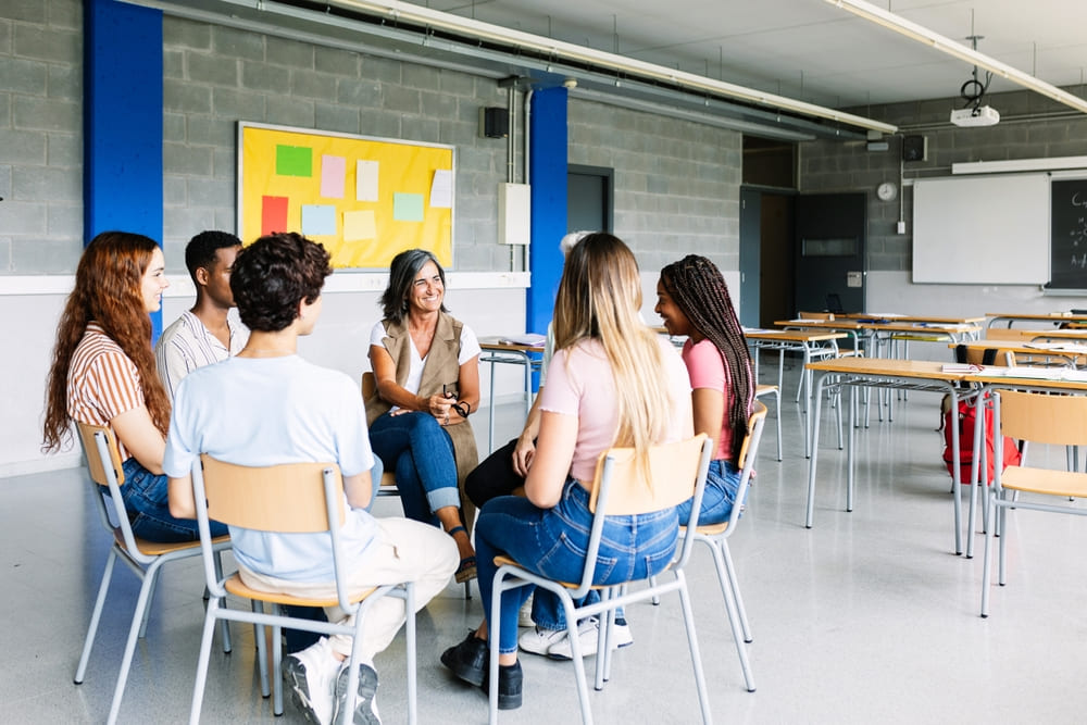 Orientadora educacional facilitando uma sessão de grupo com estudantes, promovendo a interação e o aprendizado coletivo.