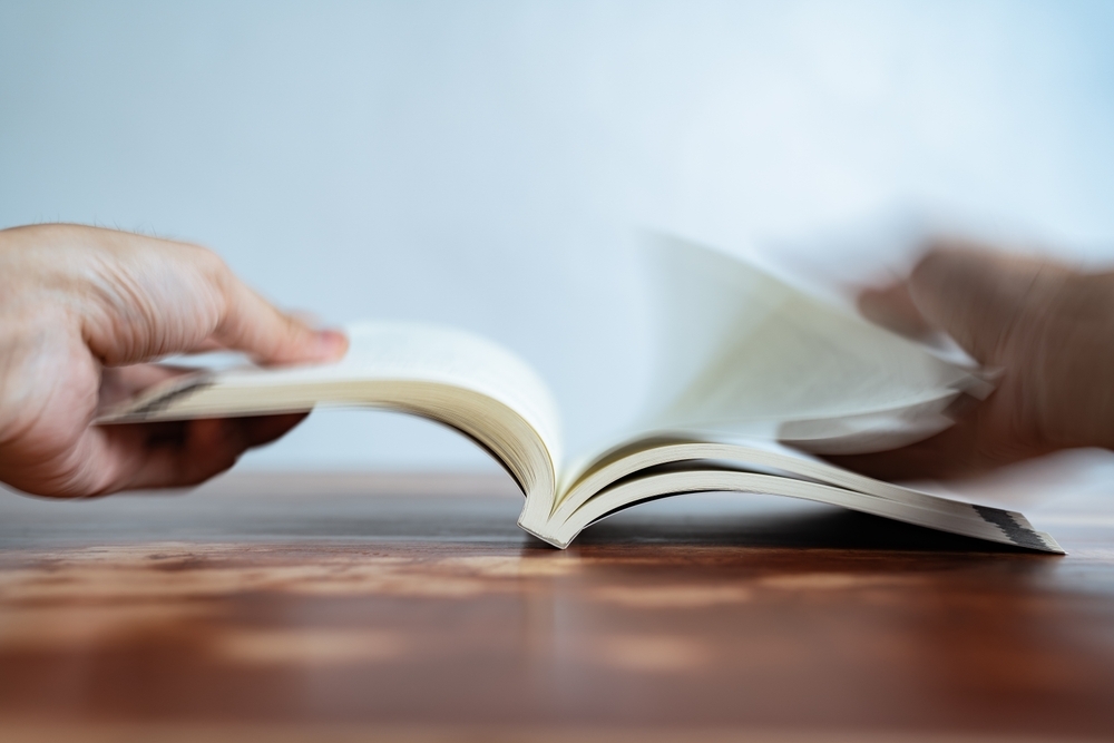 Pessoa lendo um livro com movimento de páginas, simbolizando leitura rápida em inglês.