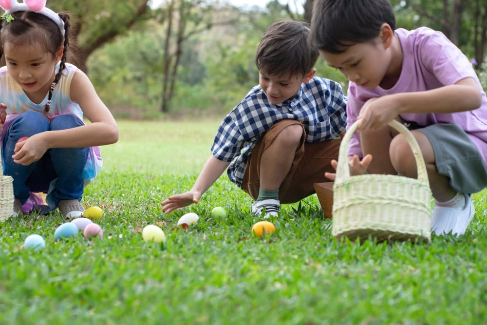 Crianças participando de uma caça aos ovos durante atividade de Páscoa ao ar livre.